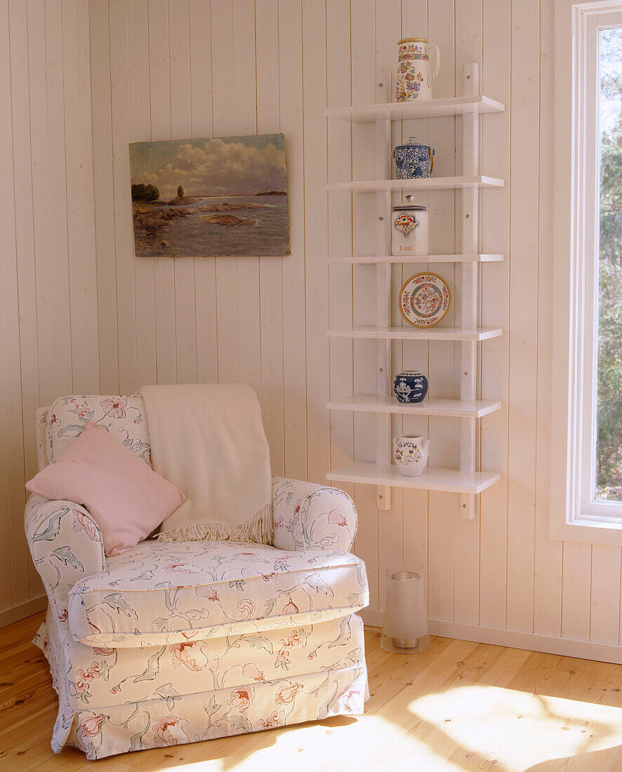 Ein Detail eines Wohnzimmers im Landhausstil mit gepolstertem Sessel