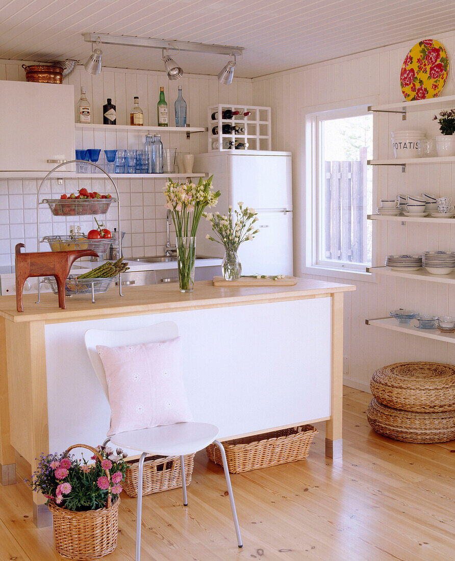 Eine moderne Küche in neutralen Farben mit zentraler Kochinsel und Holzboden