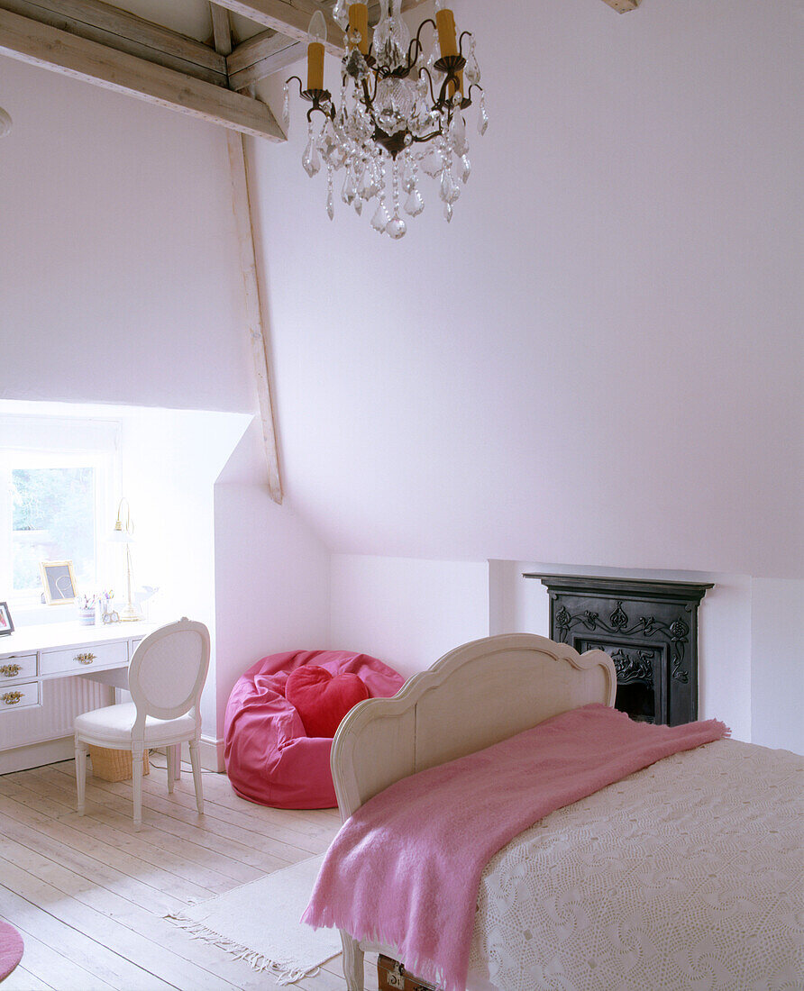 A traditional child's bedroom with a high ceiling and a chandelier suspended above the bed next to a fireplace