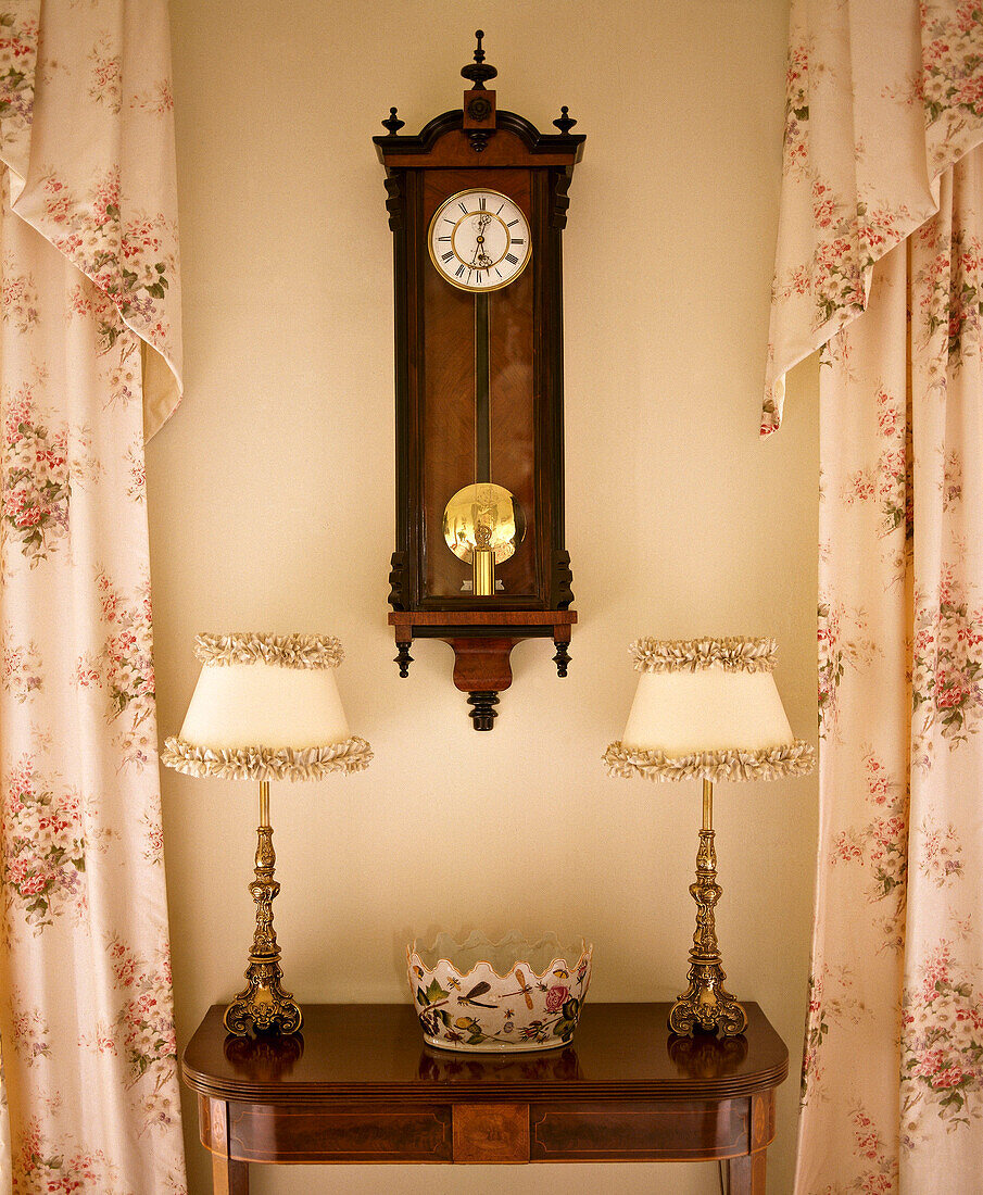 Matching lamps and wall clock with side table and patterned curtains