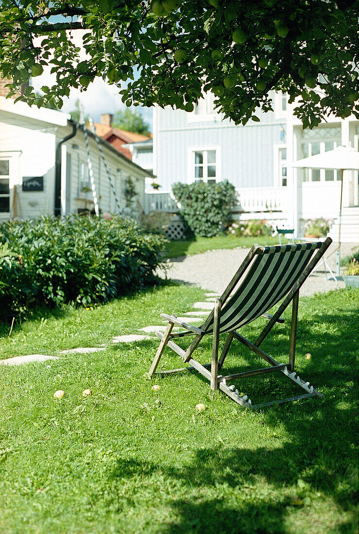 Deck chair on lawn set in shade under tree