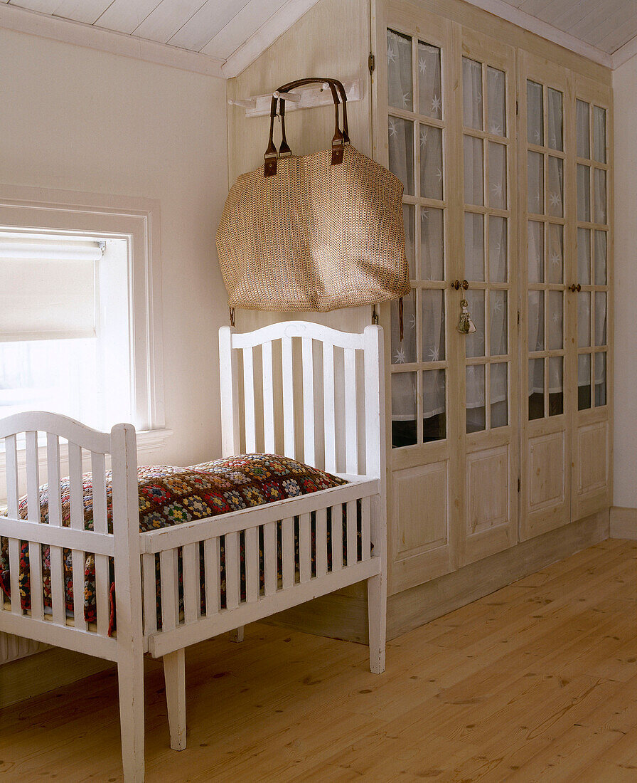 White wood cot next to built in wardrobes