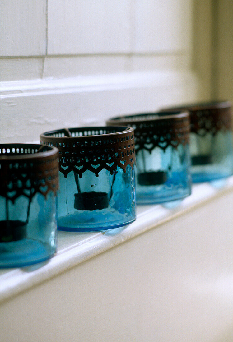 A detail of blue glass candle holders on a mantelpiece