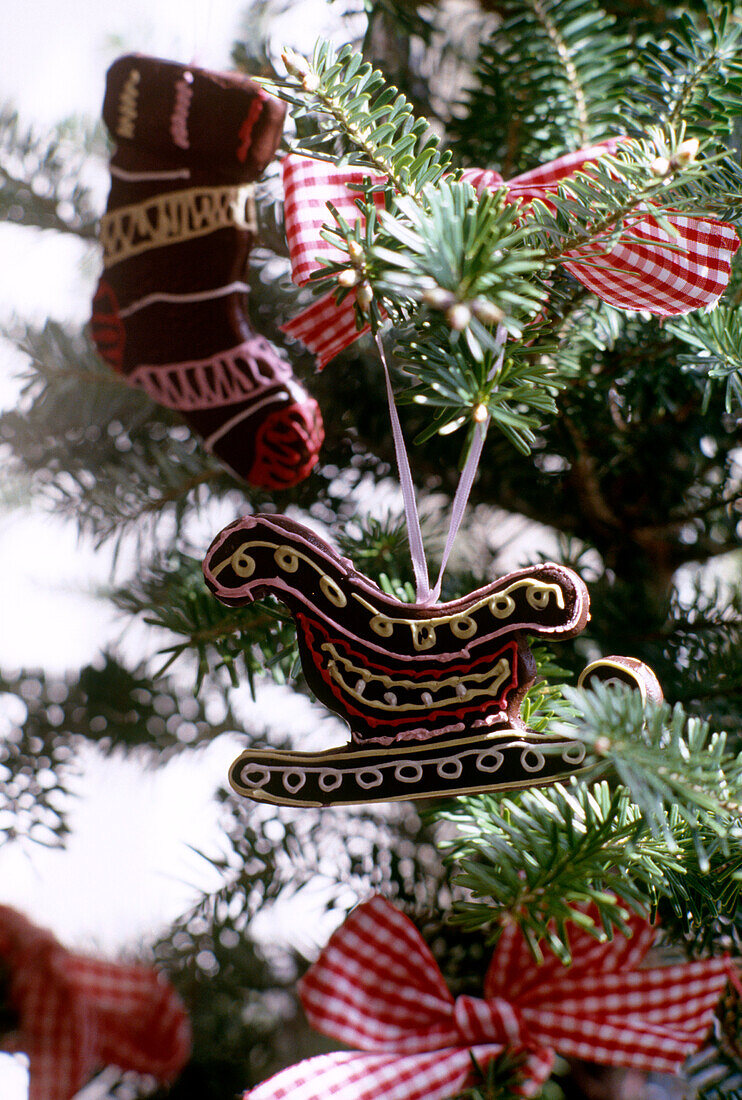 Nahaufnahme von einem Weihnachtsbaum mit Weihnachtsschmuck und rot-weißen Schleifen