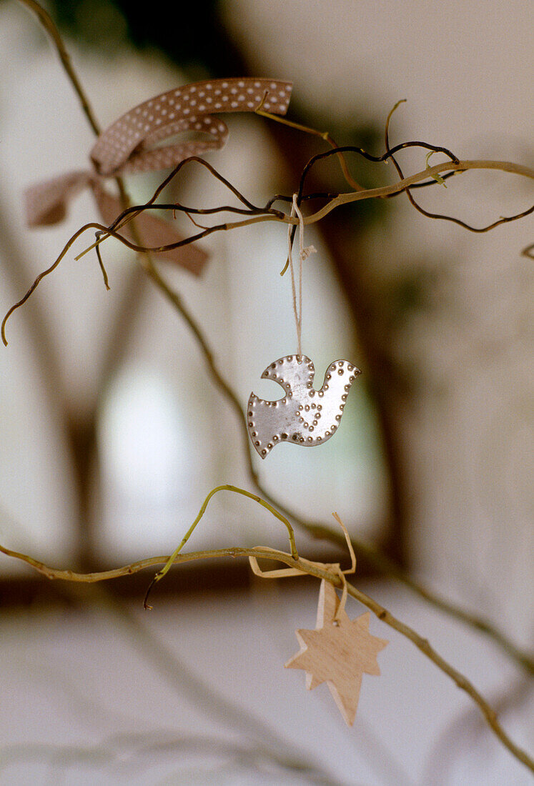Close up detail of a small silver decoration of a dove hanging from the branch of a small plant