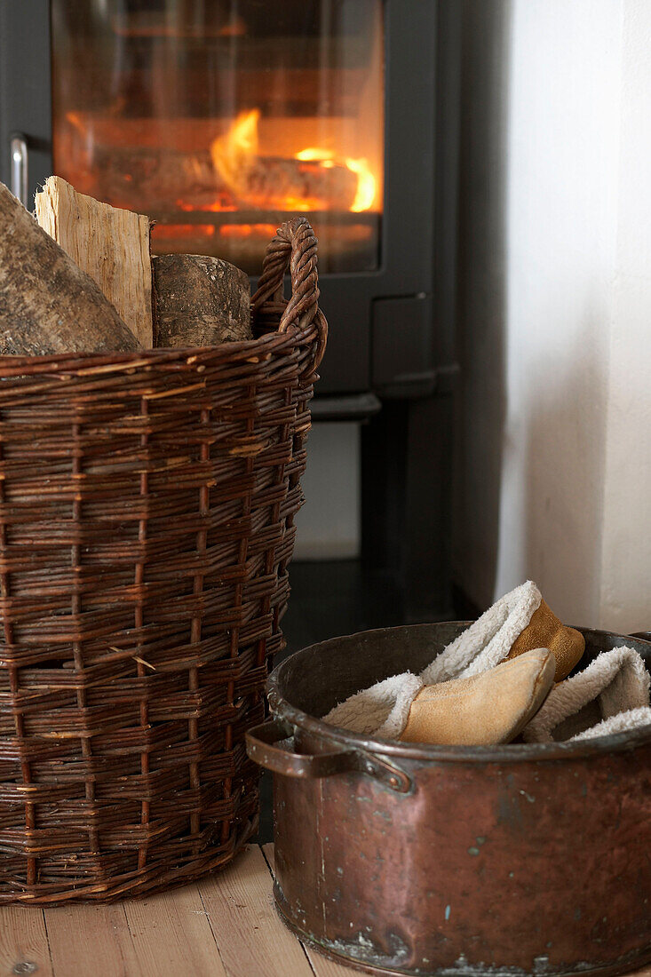 Logs in wicker basket in front of stove with lit fire