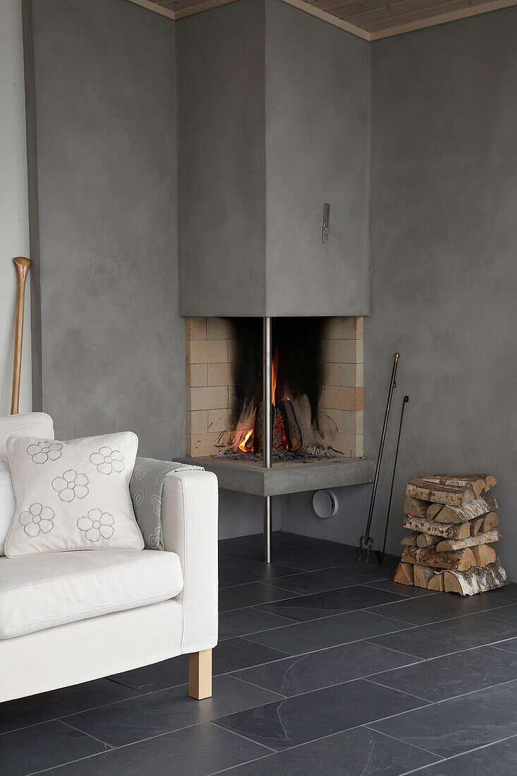 Sofa next to contemporary stove with lit fire
