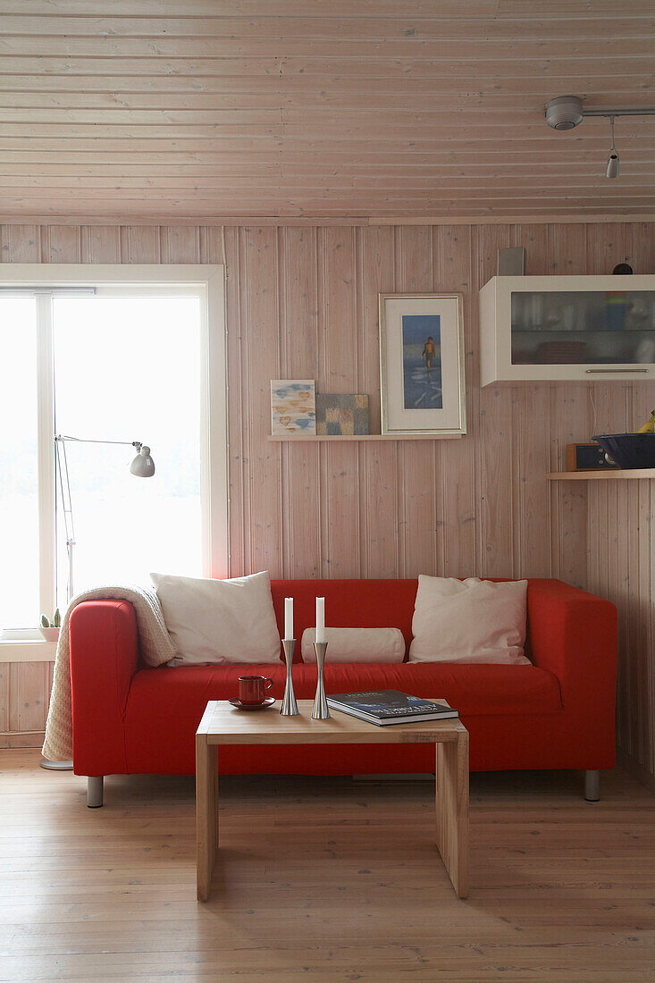Couchtisch aus Holz vor rotem Sofa in einem Zimmer im Landhausstil