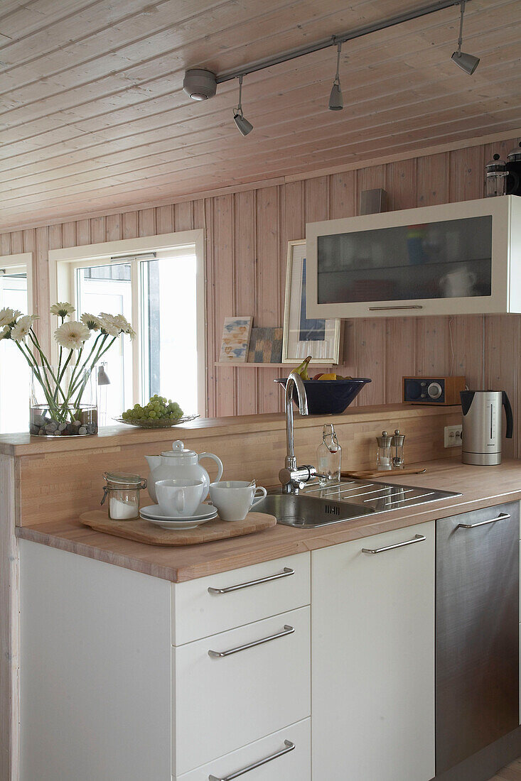 Küche mit weißen Einbaumöbeln, Holzarbeitsplatten und Spülbecken