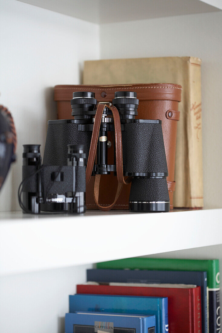 Binoculars and books on shelves
