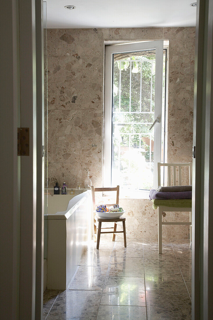 Blick durch die offene Tür auf Badewanne im gefliesten Badezimmer