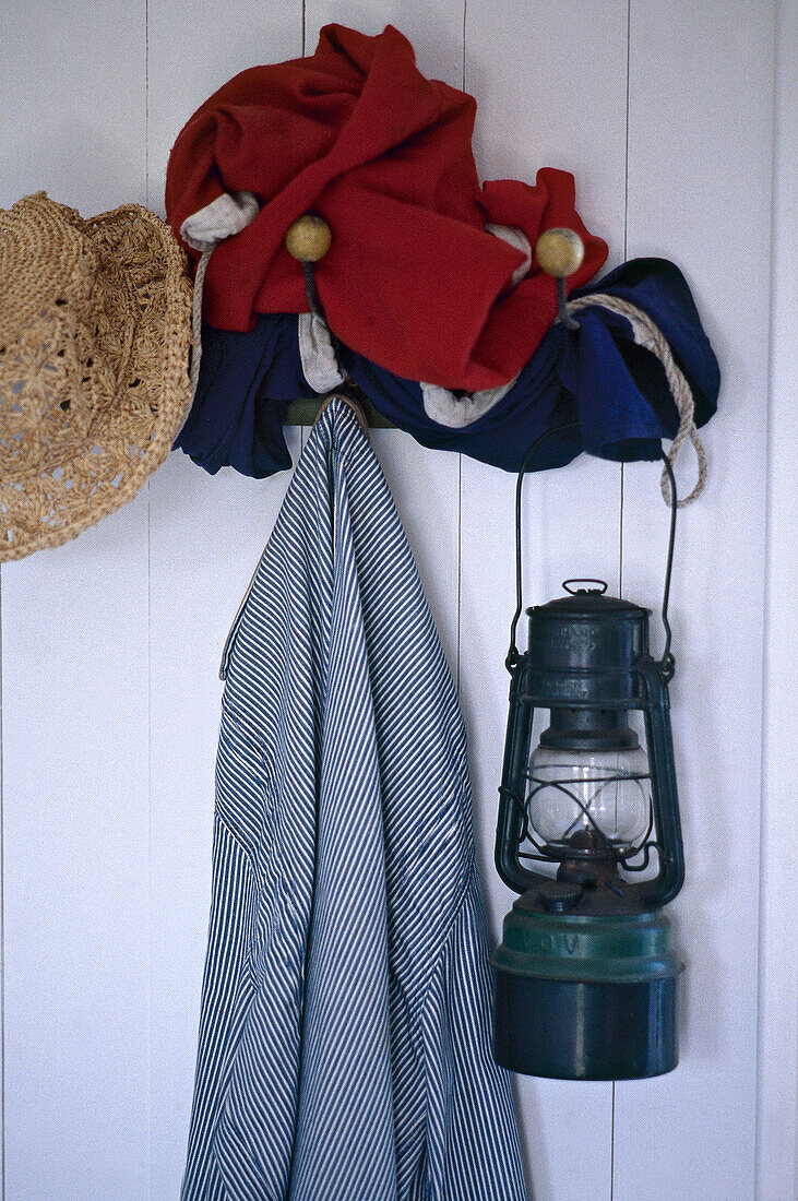Öllampe, Hut und Jacke hängen an einer Hakenleiste