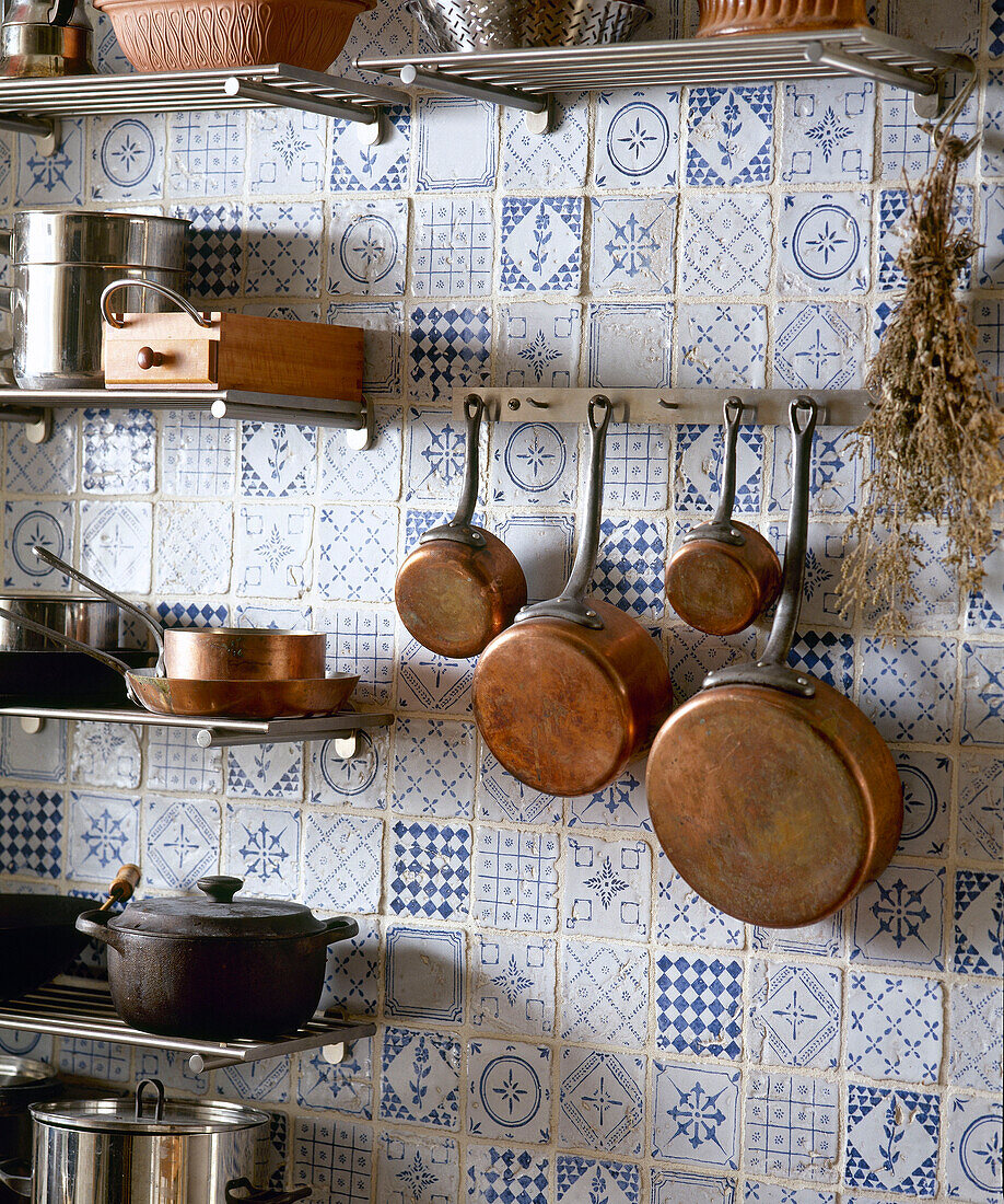 Copper pans hanging on blue tiled wall