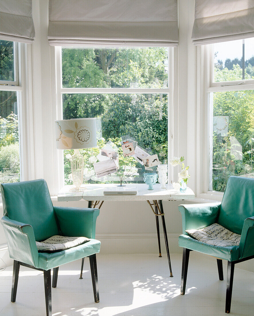 Two green upholstered chairs in bay window