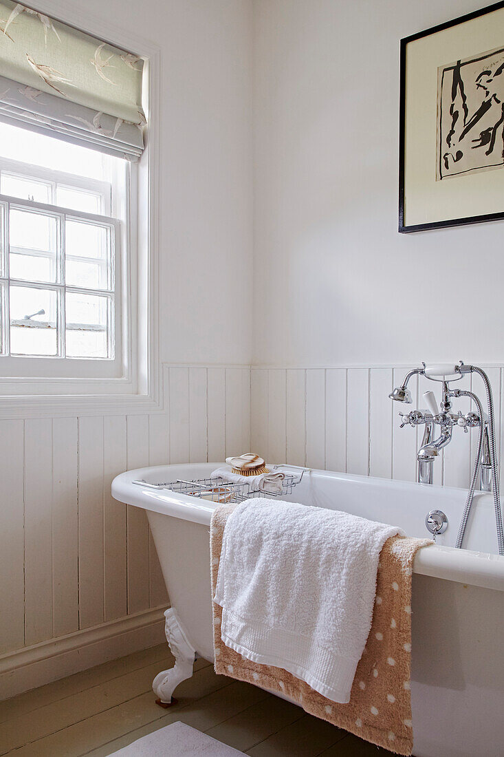 Freistehende Badewanne im weiß getäfelten Badezimmer eines Strandhauses in Port Issac, Cornwall