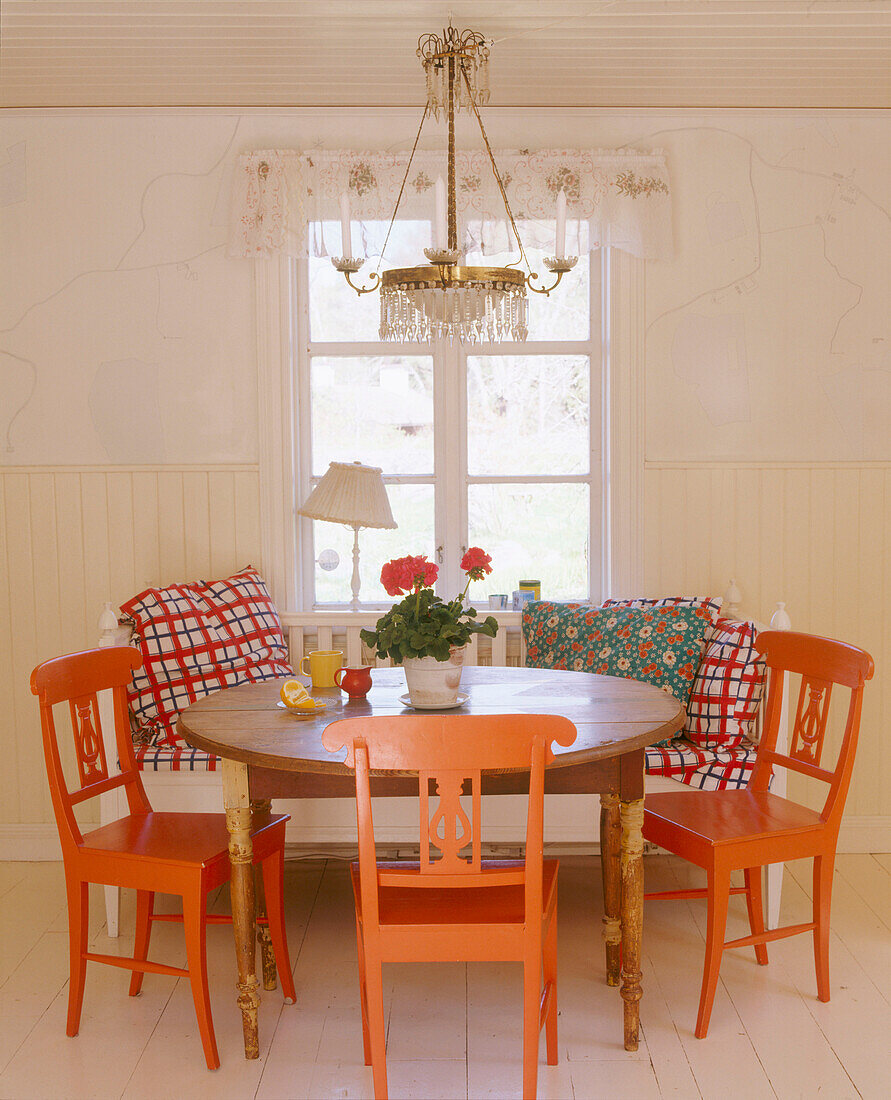Esszimmer im Landhausstil mit einer Lampe über einem Tisch, umgeben von gestrichenen Holzstühlen