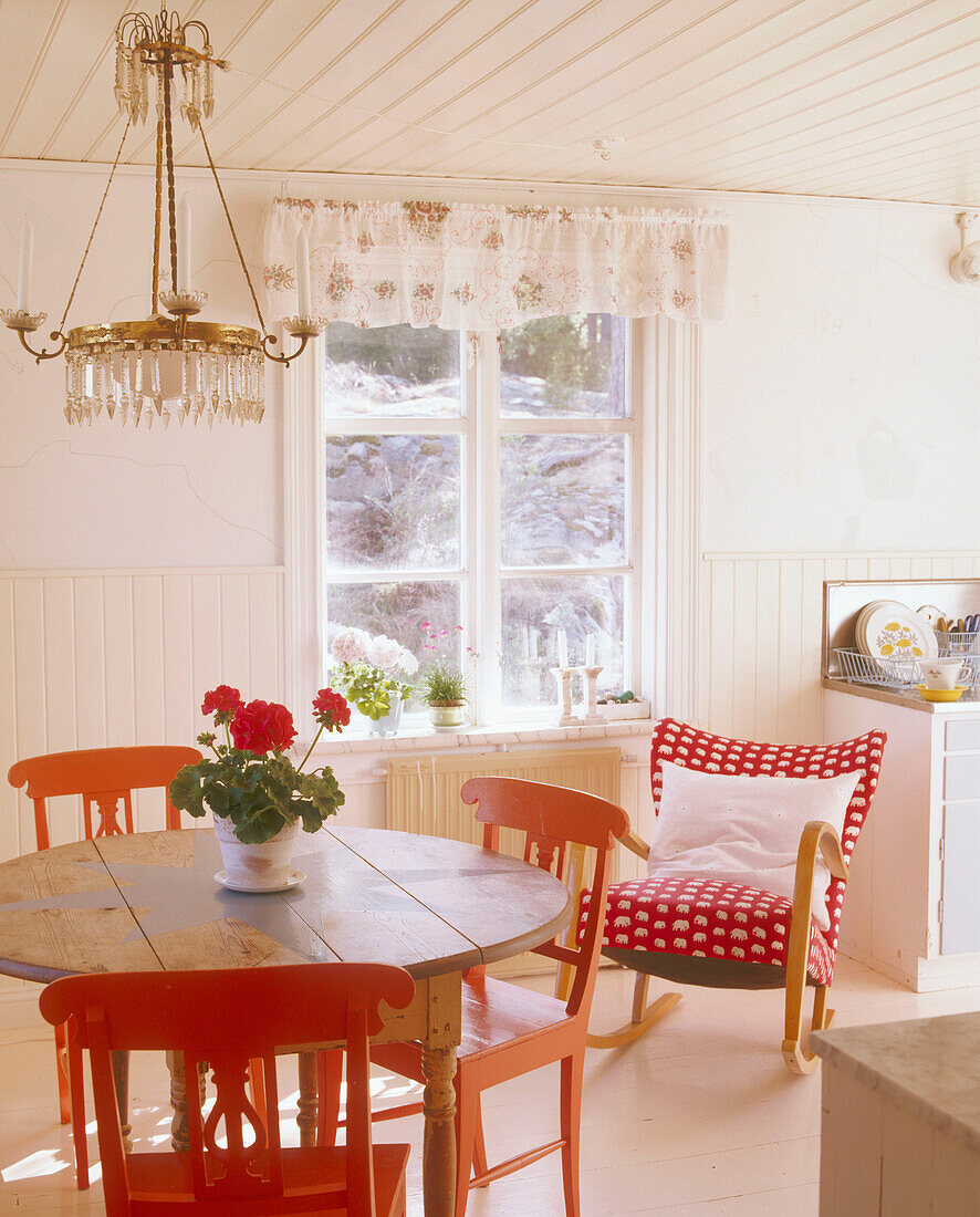 Esszimmer im Landhausstil mit einer Lampe über einem Tisch, umgeben von gestrichenen Holzstühlen