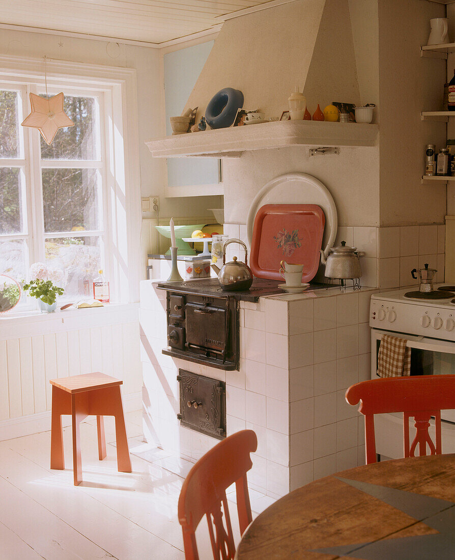 Küche im Landhausstil mit einem weißen Kachelherd und einem kleinen roten Hocker