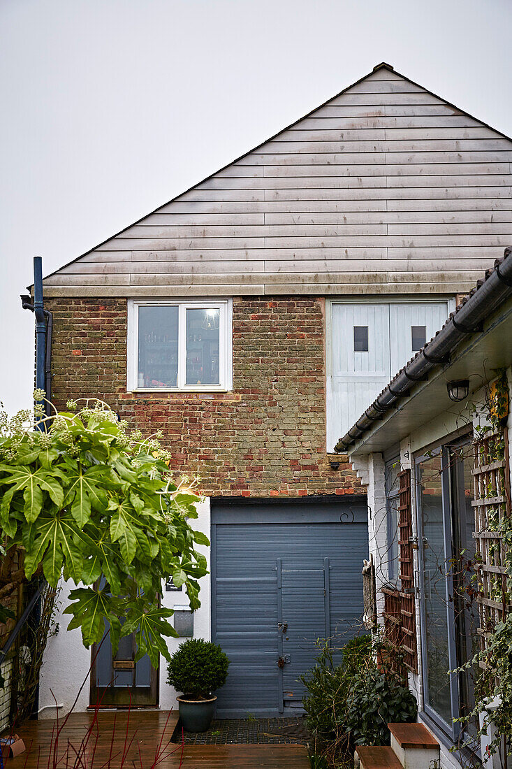 Eingangstüren und Terrassendielen einer umgebauten Scheune bei Regenwetter, Brighton, East Sussex, UK