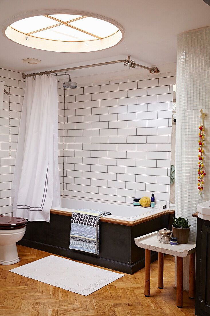Großes weiß gefliestes Badezimmer mit Oberlicht und Parkettboden in einem Haus in Brighton, East Sussex, UK