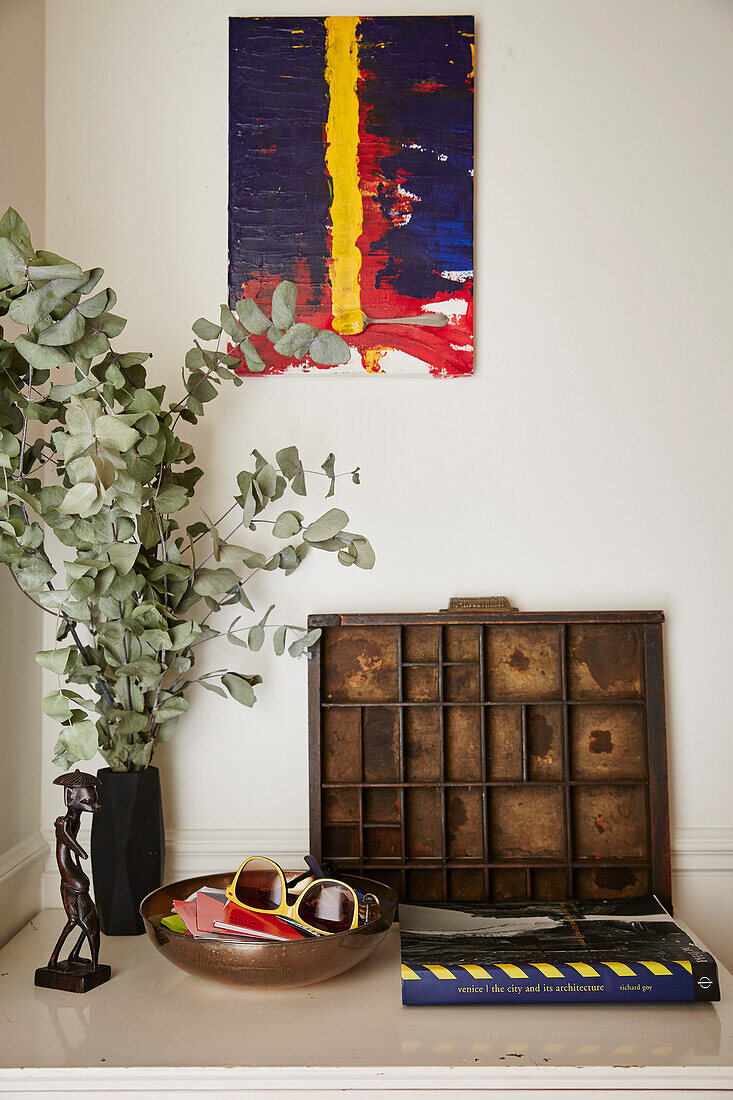 Vintage-Setzkaste, Blätterzweige in Vase und abstraktes Kunstwerk auf Leinwand im Haus der Architektin und Designerin Chantal M. in Hackney, London, UK