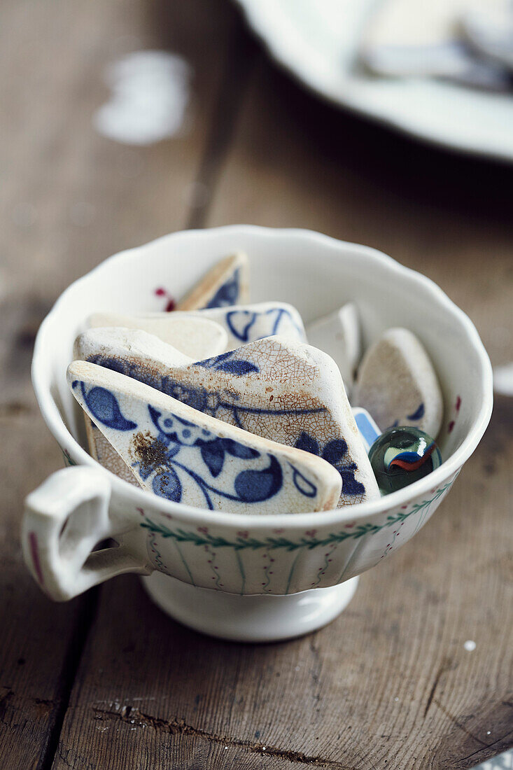 Zerbrochene Kachelfragmente in einer Teetasse im Atelier einer Stilllebenmalerin