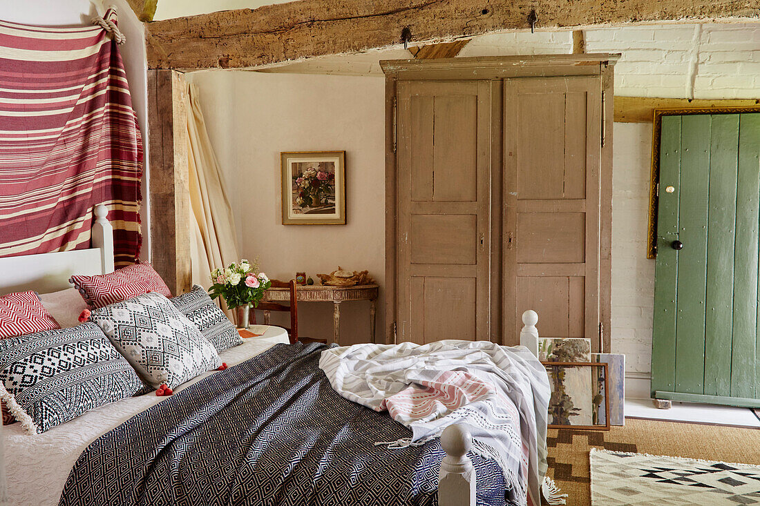 Schlafzimmer mit gestrichenem Kleiderschrank in reetgedecktem Landhaus aus dem 17. Jahrhundert in Hampshire, England, UK