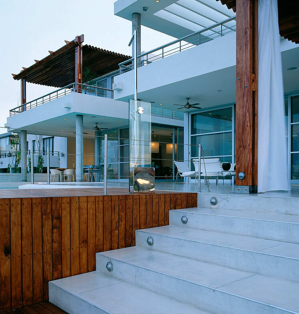 Contemporary house exterior with steps leading up to decked pool area and terrace