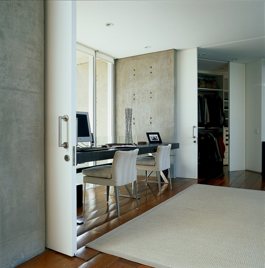 Contemporary open plan dual home office and bedroom space with sliding partition walls and large glass panelled windows