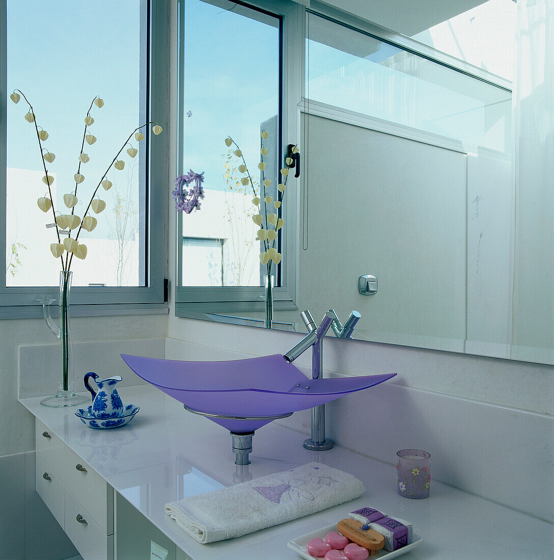 Modernes weißes Badezimmer mit großem Spiegel und farbigem Glaswaschbecken