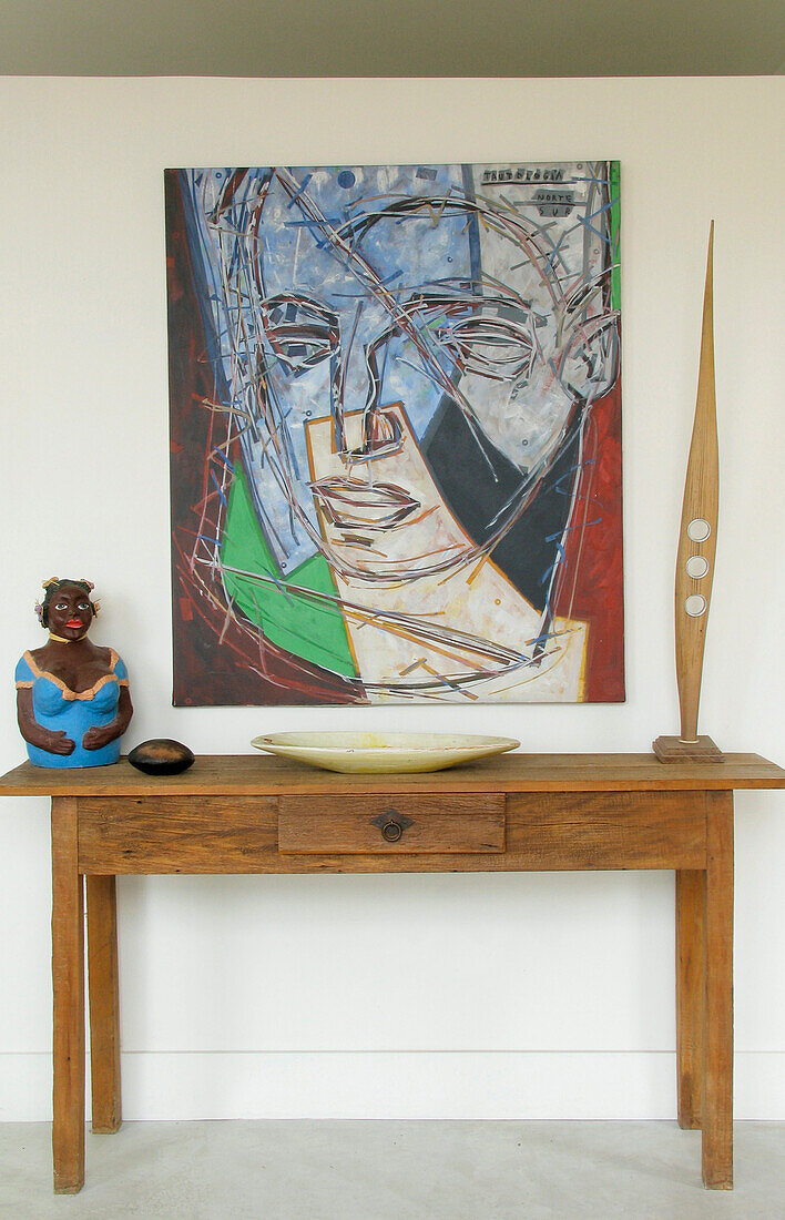 Holztisch im Flur mit Skulptur, Dekogegenständen und modernem Wandbild