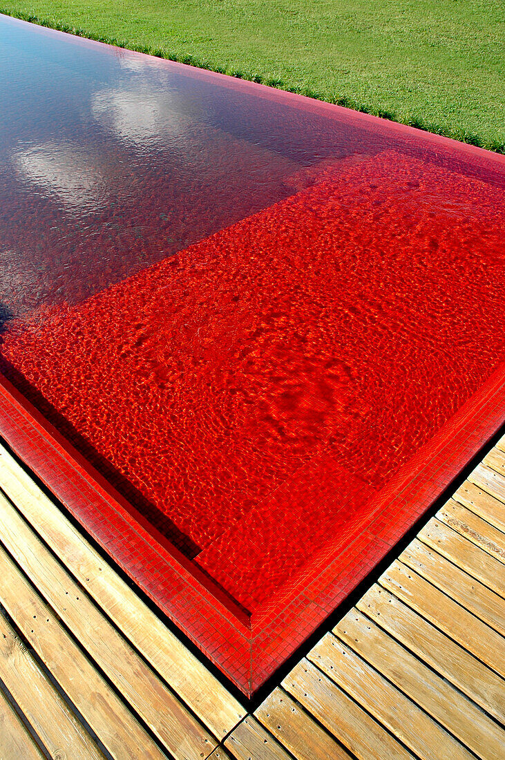 Swimming pool with red venecitas tiling and wooden decking