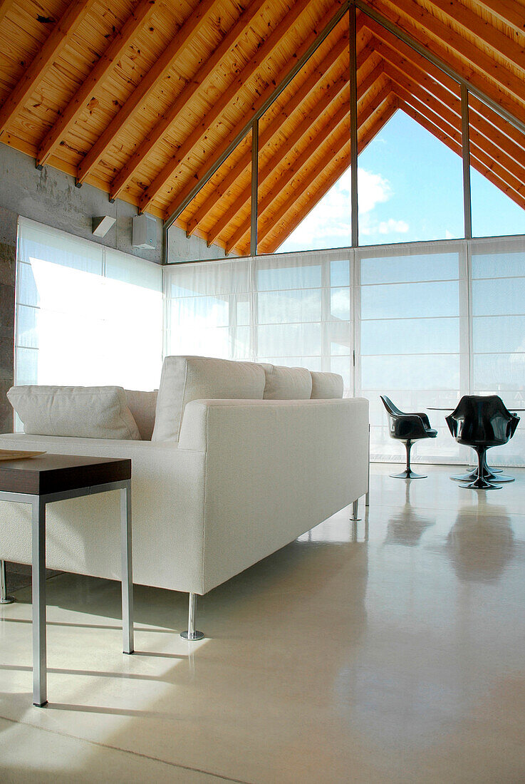 Wohnzimmer mit Betonböden, weißen Wänden, Paneelen aus Stahlbeton, Vorhängen aus Gaze und Baumwolle