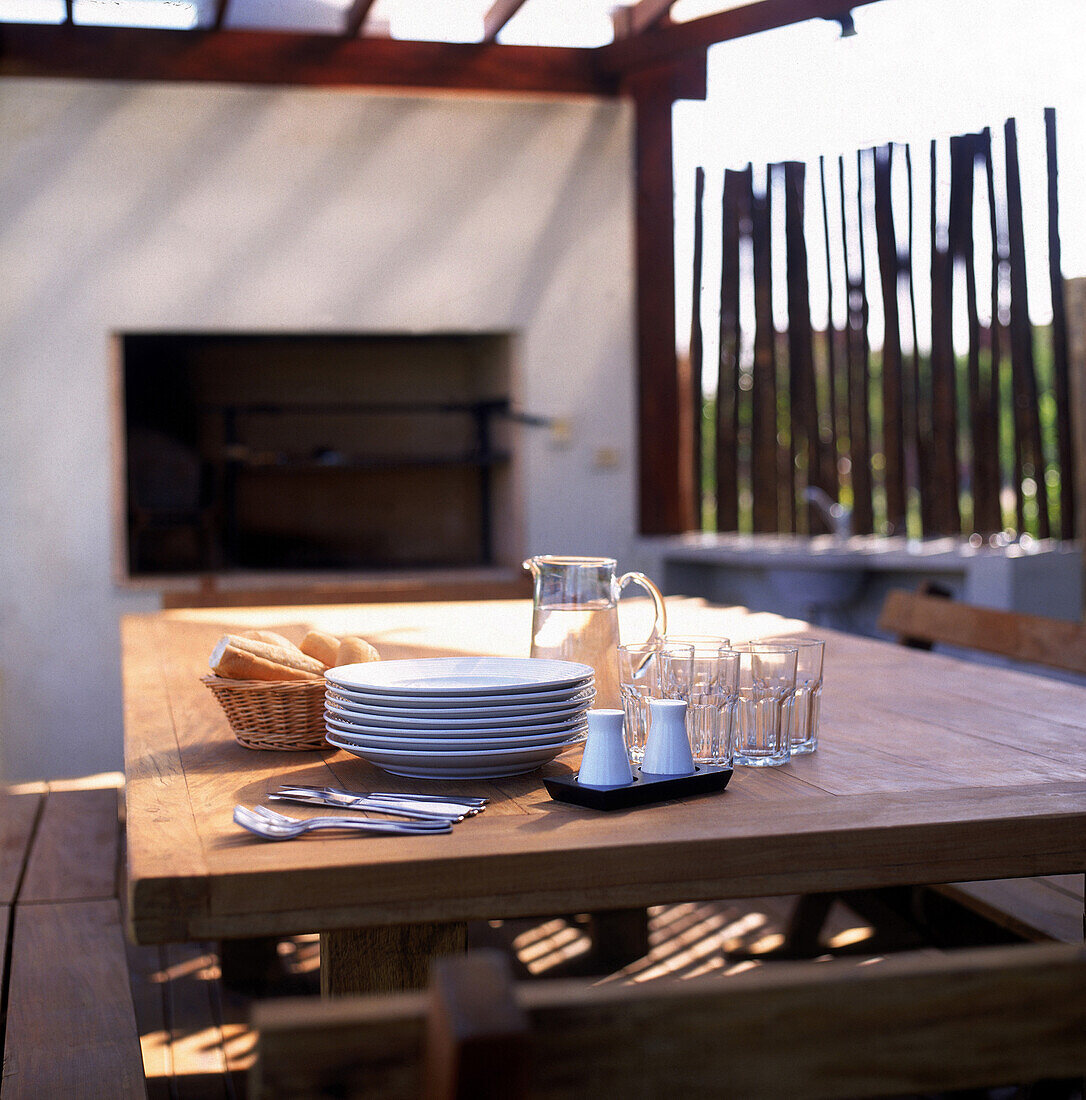 Grillbereich mit Geschirr und einer Wand aus vertikal aufgestellten Holzscheiten