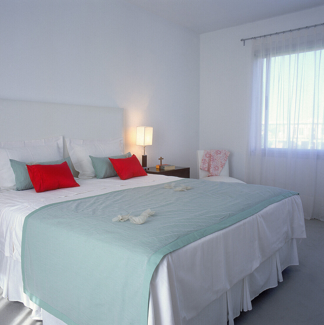 Bed with leather upholstered headboard and white bedspread with matching cushions