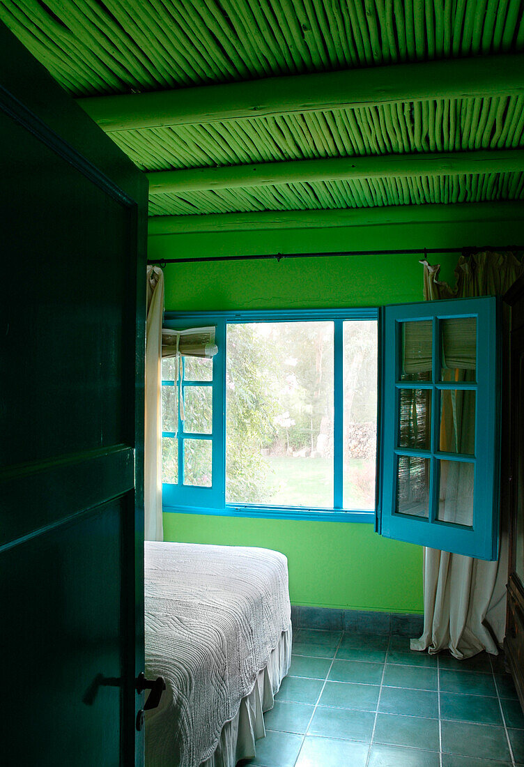 Türkis bemalter Fensterrahmen in einem Schlafzimmer in kräftigem Grün