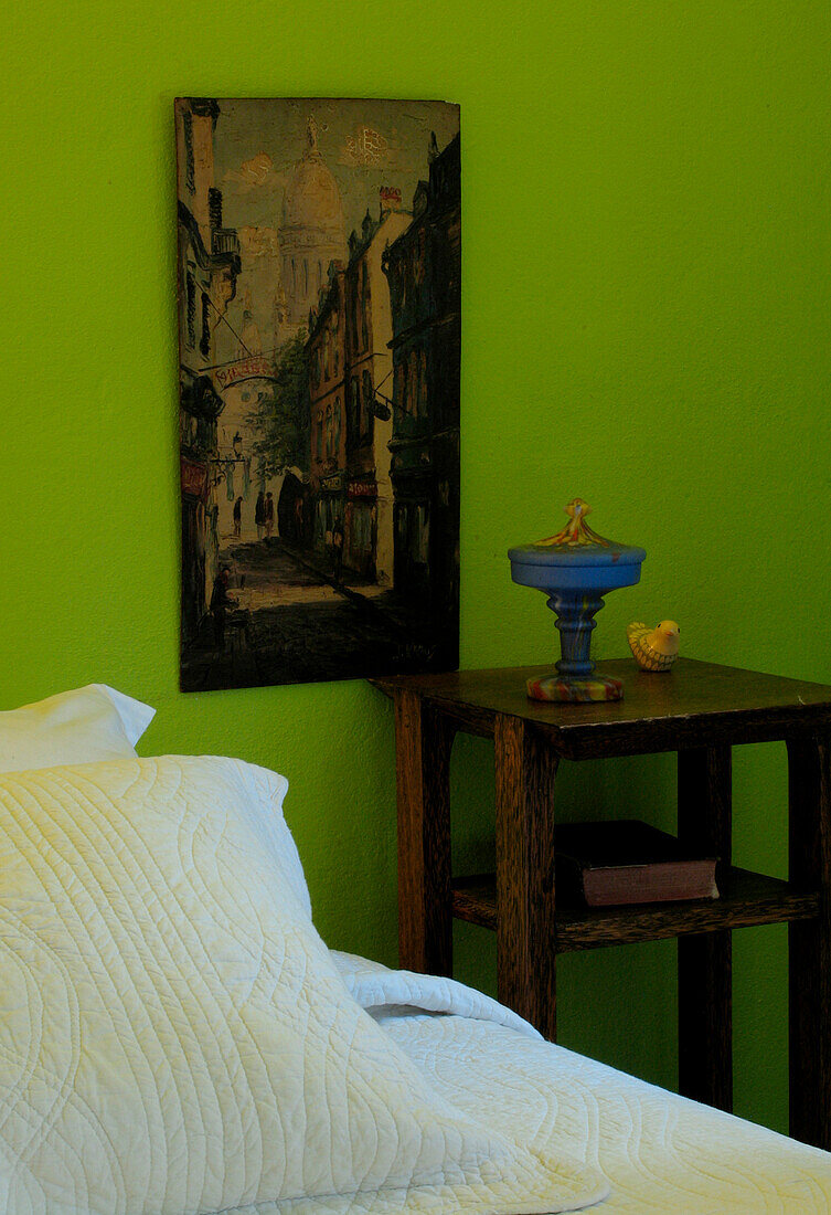 Wooden antique night stand with artwork next to bed
