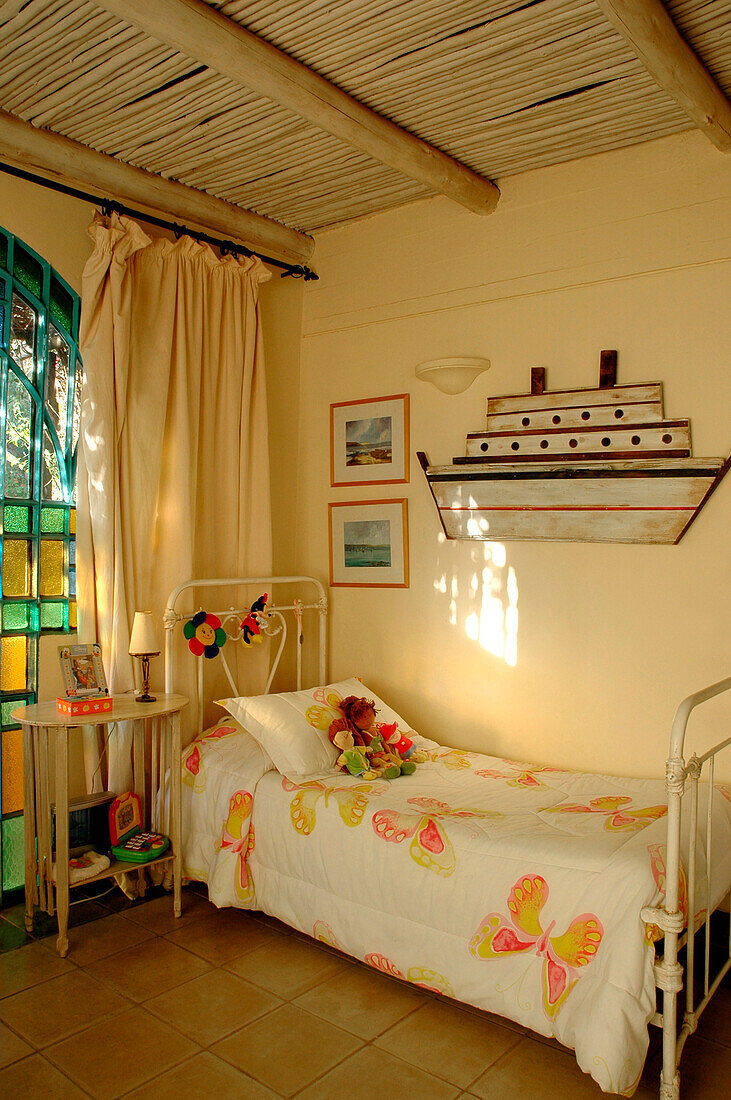 Schmiedeeisernes Bett in einem Kinderzimmer mit nautischem Kunstwerk
