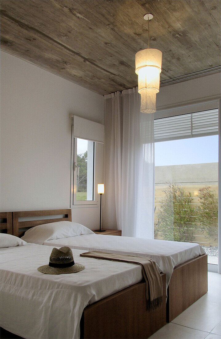 Weiß gestrichenes Bett mit freistehendem Kopfteil in Schlafzimmer mit Holzeinbauschränken