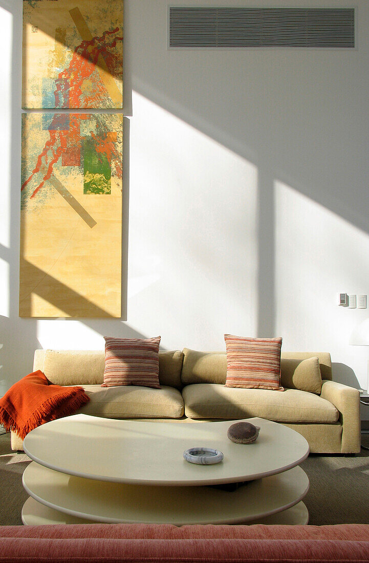 Seating area with sofa upholstered in neutral fabric and artwork by Alberto Carbi