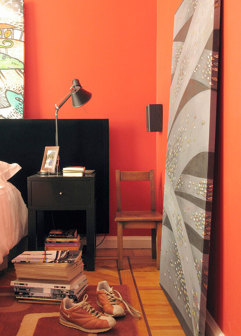 Kunstwerk an der Wand eines rot gestrichenen Schlafzimmers gelehnt
