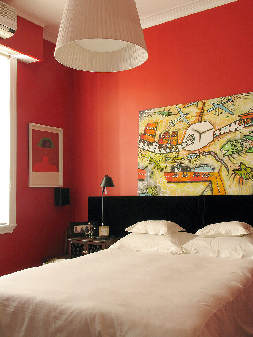 Weißer Bettbezug in rotem Zimmer mit zeitgenössischem Kunstwerk