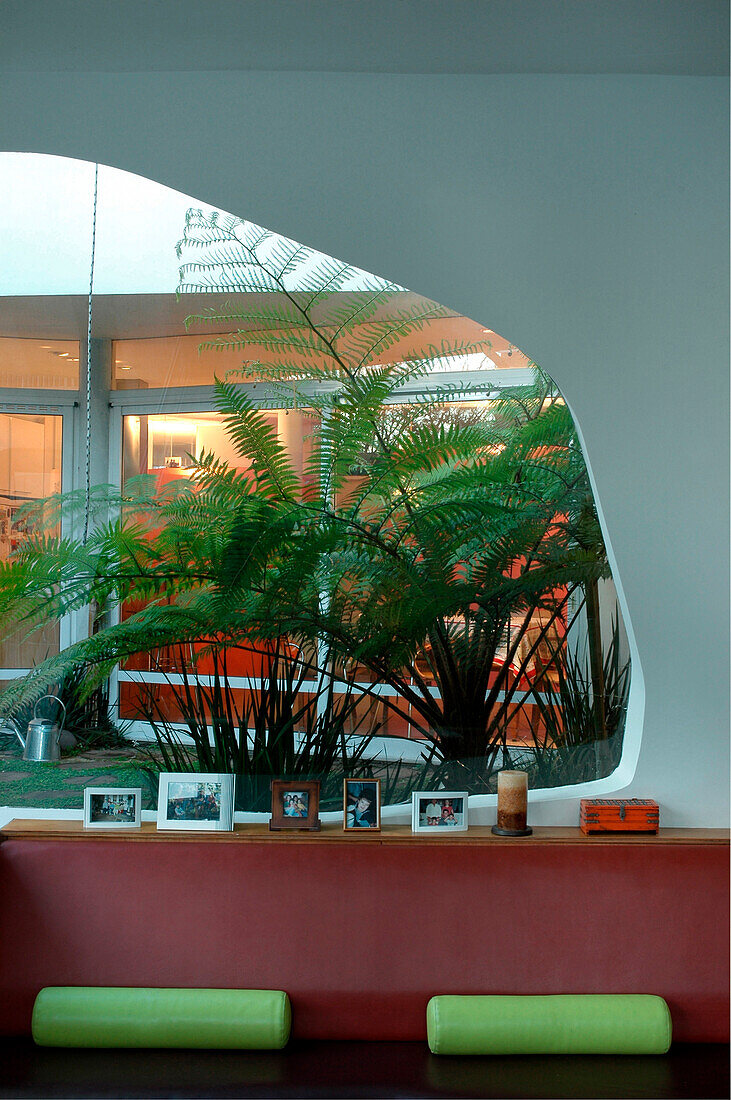 Leather seating area under large mis-shaped window allowing exterior to blend with interior