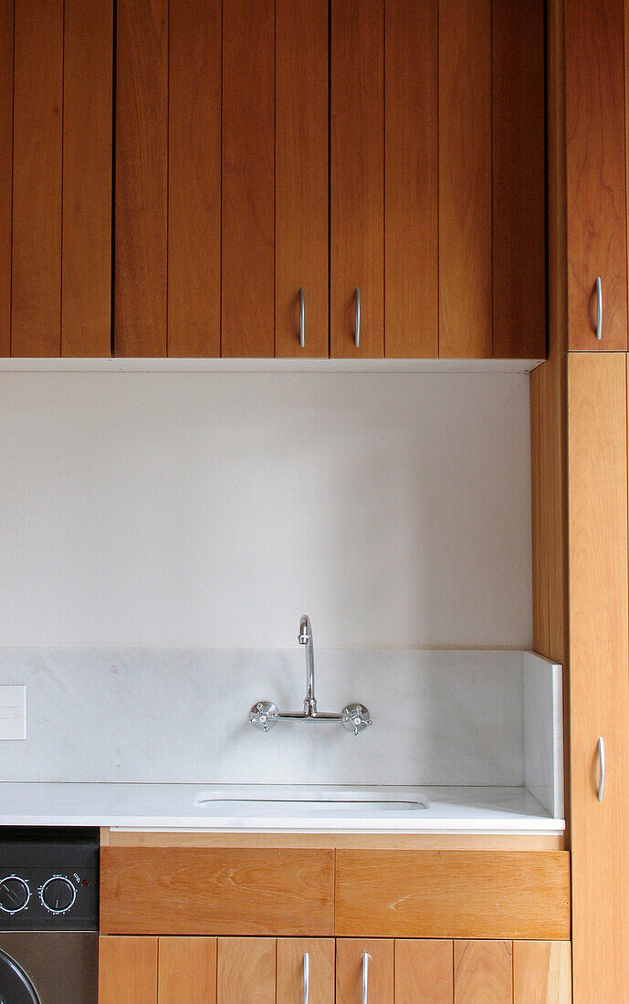 Kitchen sink and mixer tap with white marble worktop and splashback and cedar wood units