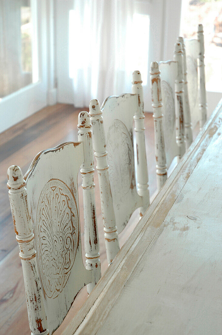 Weiß gestrichene Stuhllehnen am Esstisch
