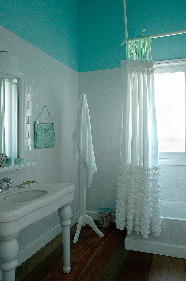 Türkisfarbenes und weißes Badezimmer mit Keramik-Waschtischunterschrank