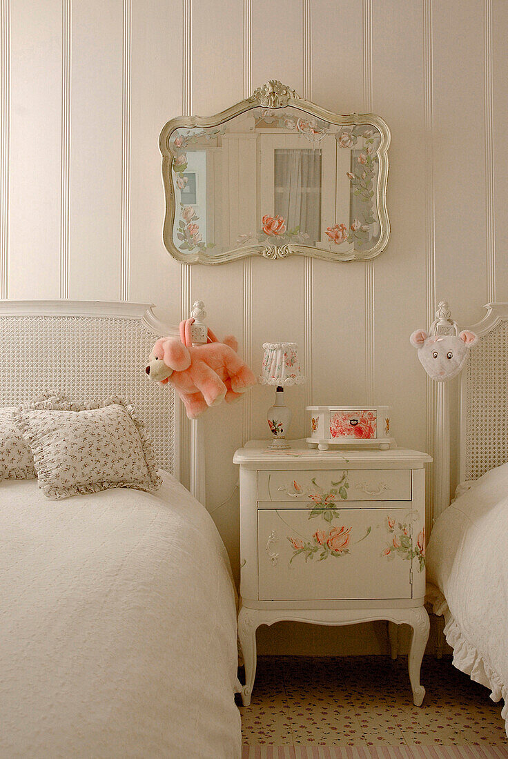 Mirror above nightstand in child's room with twin beds