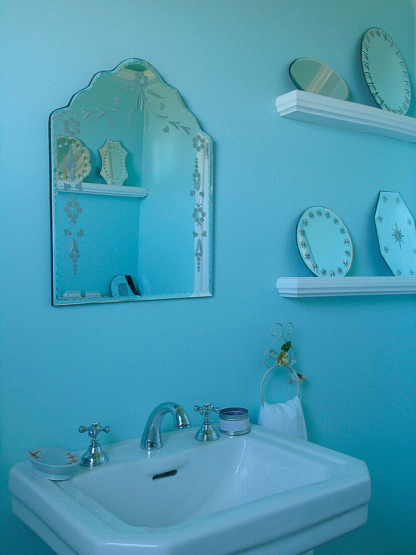 Washstand below engraved mirror and shelves with decorative plates