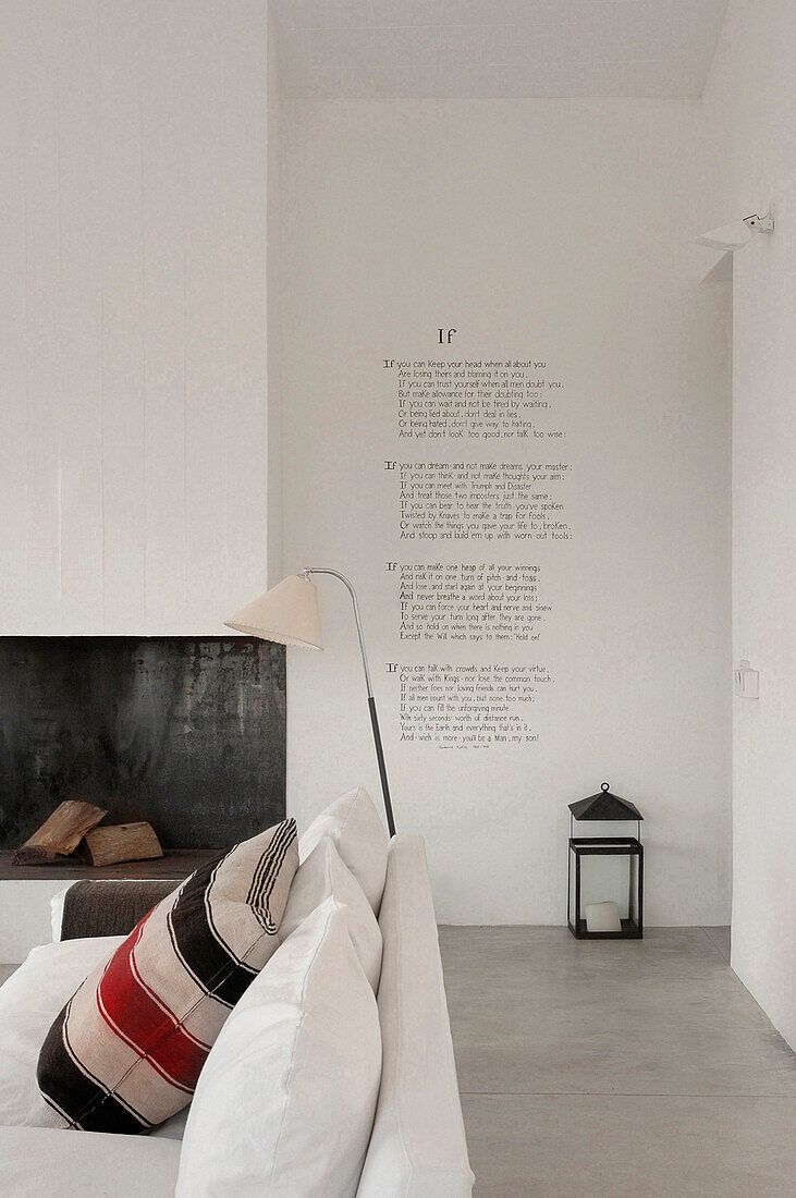Wohnzimmersofa mit gestreiften Kissen auf Sofa, Kamin und Poesie-Strophen an der Wand
