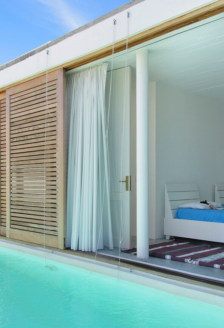Lapacho wood sliding shutters of bedroom open directly to swimming pool